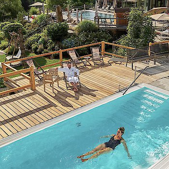 Ein paar gleitet im wohlig warmen Solepool im Freien. Wellnesshotel Riedlberg